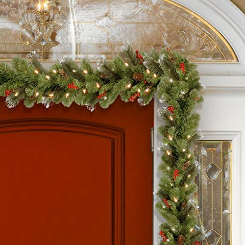 Festive holiday garland with lights on a red door.